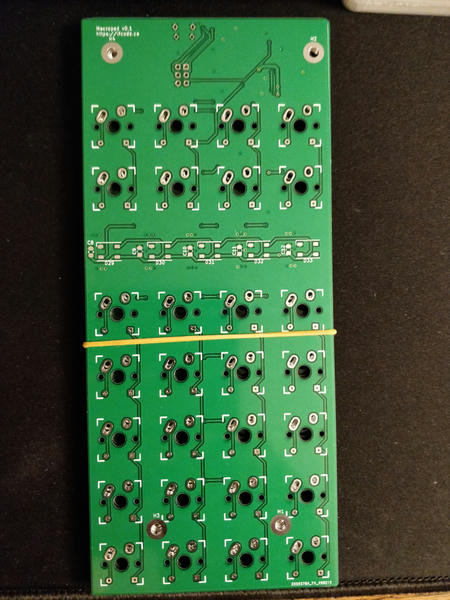 Photo of the front of a stack of rectangular green number pad shaped circuit
boards with no parts populated yet.
