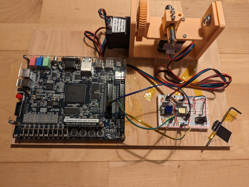 Piece of plywood with a DE1-SoC development board on it next to a breadboard
with stepper drivers and a 3d printed assembly with a rotation/pitch stage.